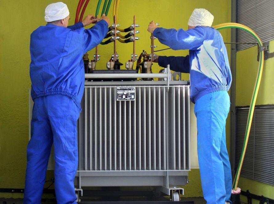electricians working at high voltage power transformer