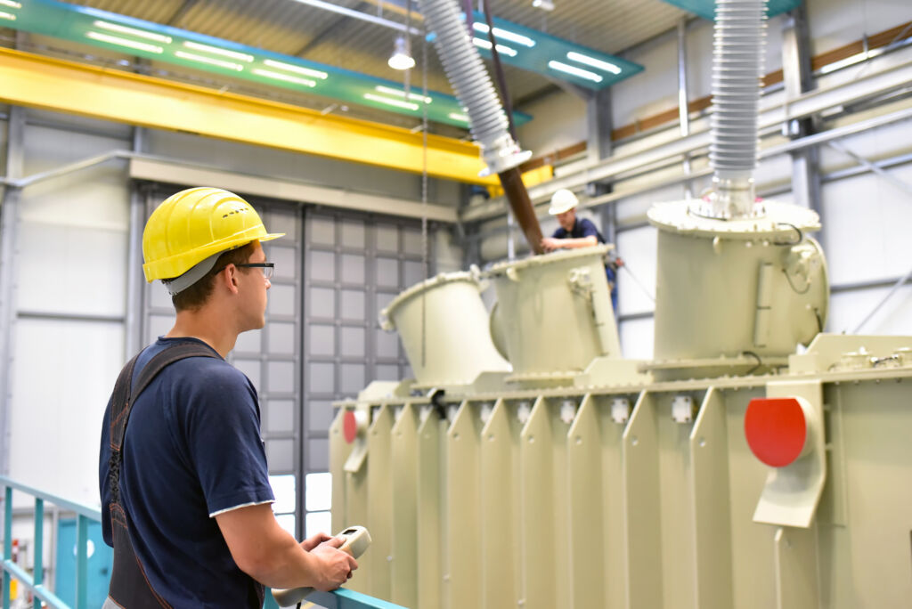 operator installs a transformer in an industrial plant in mechanical engineering