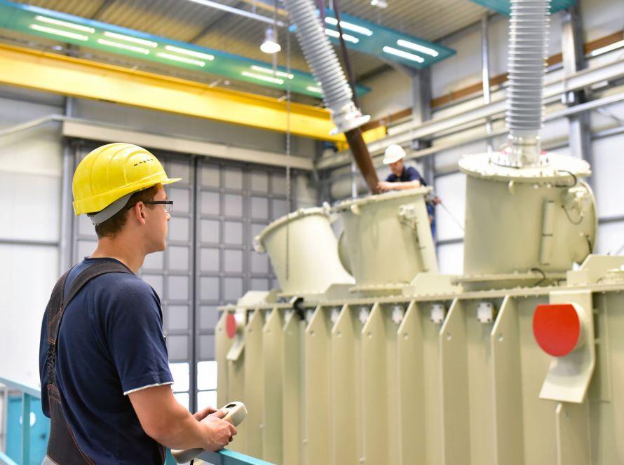 operator installs a transformer in an industrial plant in mechanical engineering